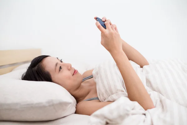 Woman on bed and using mobile phone — Stock Photo, Image