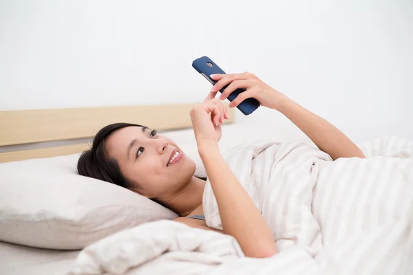 Mulher na cama e usando telefone celular — Fotografia de Stock