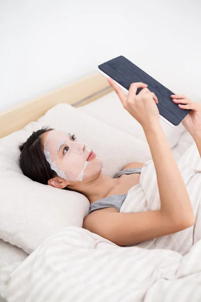 Vrouw met behulp van de tablet pc en gezichts masker — Stockfoto