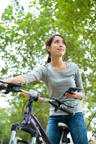 Woman using cellphone while cycling — Stock Photo, Image