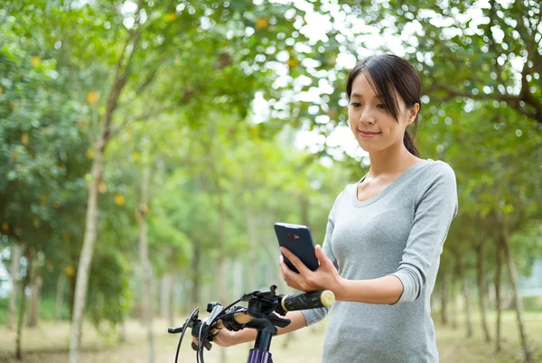 Vrouw met behulp van mobiele telefoon tijdens het fietsen — Stockfoto