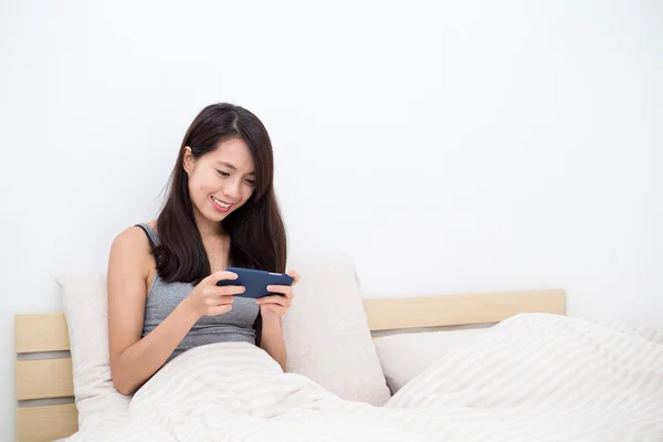 Wanita bermain game di smartphone di tempat tidur — Stok Foto