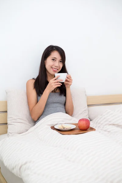 Frau frühstückt morgens im Bett — Stockfoto