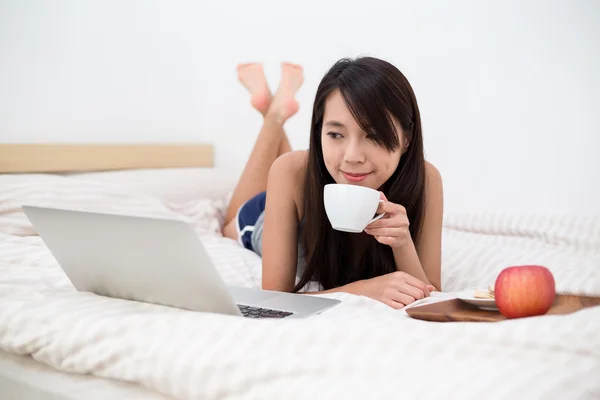 Mulher com laptop tendo o café da manhã na cama — Fotografia de Stock