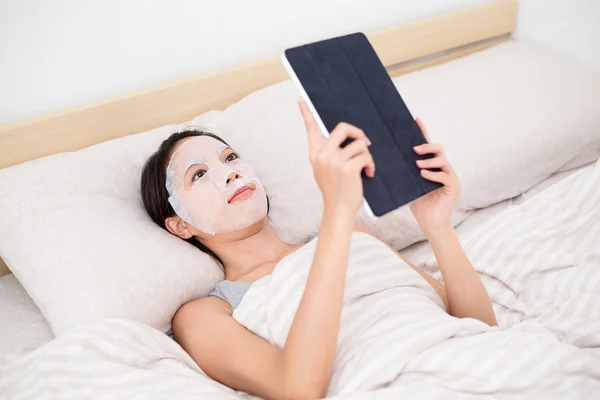 Vrouw met gezichts masker en tablet pc — Stockfoto