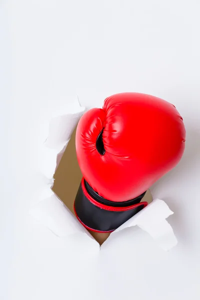 Mão na luva de boxe através do furo de papel — Fotografia de Stock