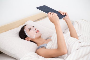 kadın yüz maskesi tablet PC'yi kullanma