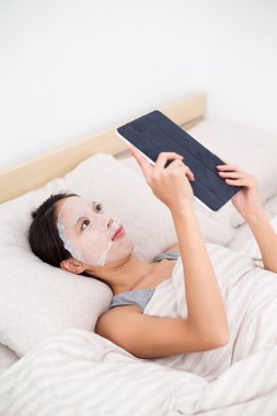 kadın yüz maskesi tablet PC'yi kullanma