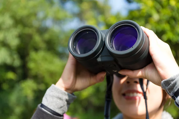 Woman looking through binoculars at outdoors — Stock Photo, Image