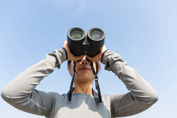 Woman looking through binoculars at outdoors — Stock Photo, Image