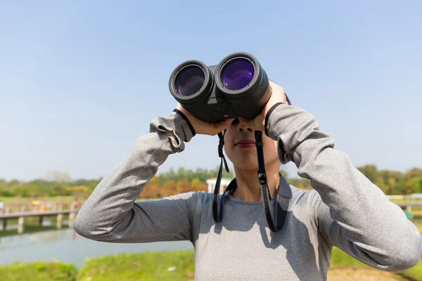 Kvinnan tittar genom kikare på utomhus — Stockfoto