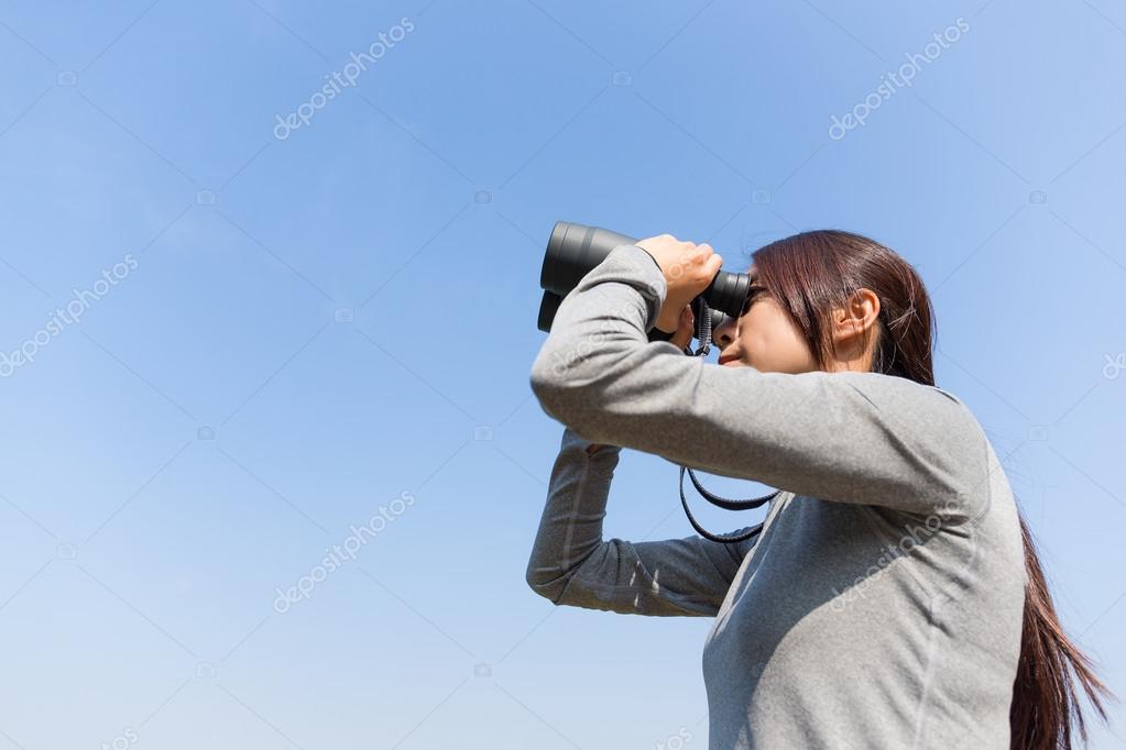 Woman looking through binoculars at outdoors — Stock Photo
