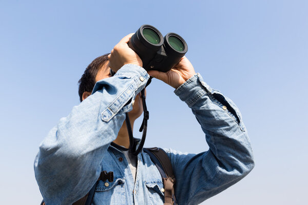 Man looking thoguh binocular and hold up