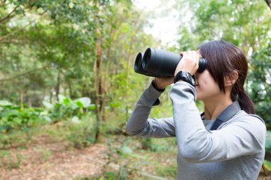 woman using binoculars at forest clipart