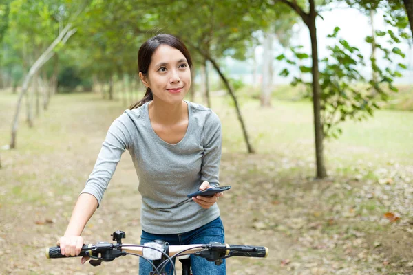Frau nutzt Smartphone und fährt Fahrrad — Stockfoto