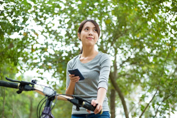 Donna utilizzando smartphone e andare in bicicletta — Foto Stock