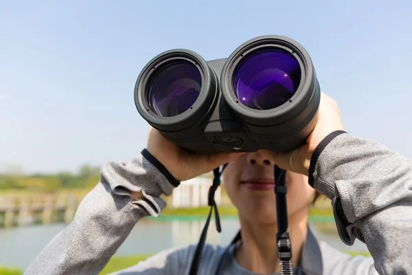 Woman looking through binoculars at outdoors — Stock Photo, Image