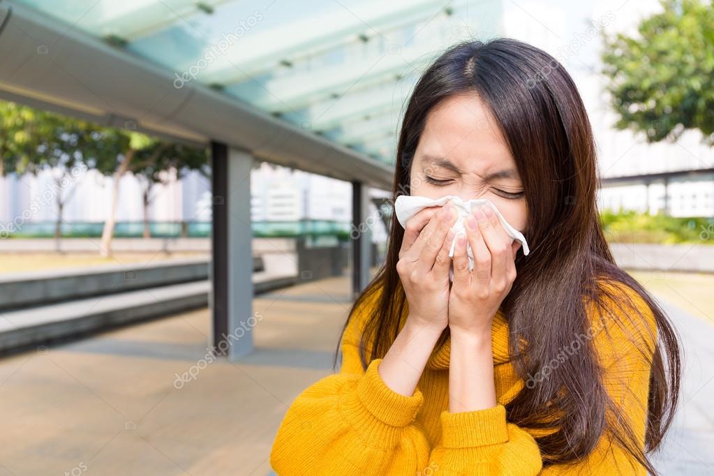 Asian young woman blowing nose