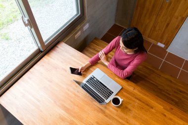 Asyalı kadın cep telefonu ve dizüstü bilgisayar kullanarak