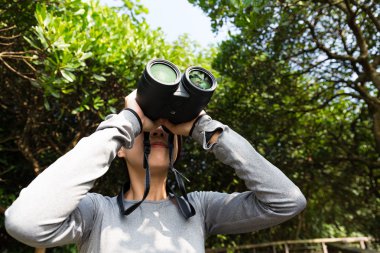 woman using binoculars at forest clipart