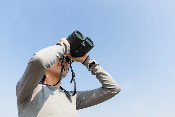 Frau blickt durch Fernglas ins Freie — Stockfoto