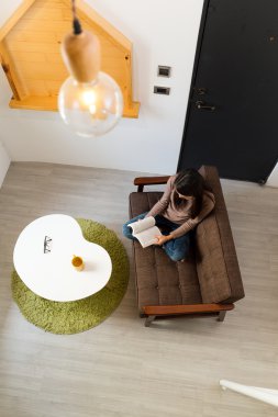 Kadın evde kitap okuyor.