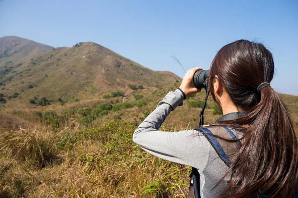 Young woman watching though binocular — Stock Photo, Image