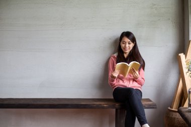 Kadın evde kitap okuyor.