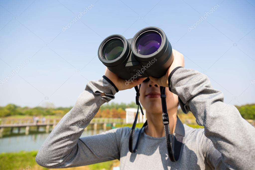 Woman looking through binoculars at outdoors — Stock Photo