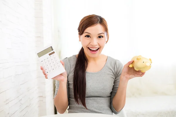 Mujer sosteniendo una calculadora y alcancía — Foto de Stock