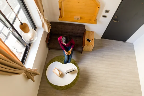 Mujer joven sentada con la tableta en casa — Foto de Stock