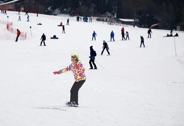 Young girl in the form of a ski down the mountain on a snowboard — Stock Photo, Image