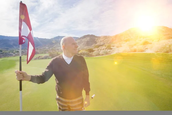在高尔夫球场上举着高尔夫球旗的老年高尔夫球手 — 图库照片