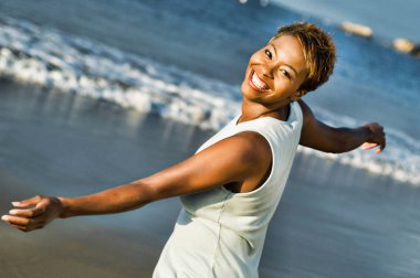 Sahilde tatilin tadını çıkaran neşeli Afrikalı Amerikalı kadın portresi.