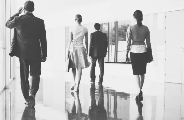 オフィスの大理石の床を歩くビジネスの人々の黒と白の写真 — ストック写真