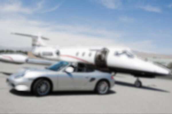 Blurred photo of Convertible car and private jet