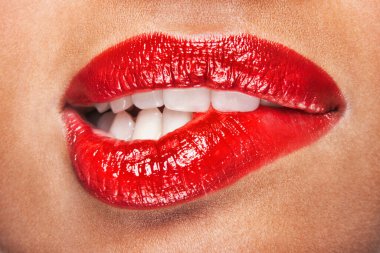 Kırmızı dudakları ısıran şehvetli kadının yakın çekimi.