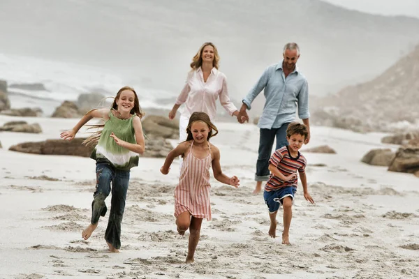 Niños Alegres Corriendo Playa Con Padres Caminando Fondo — Foto de Stock