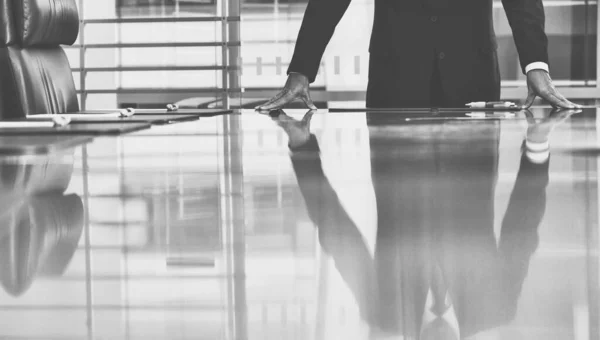 Black and white photo of Businessman standing with hands on conference table