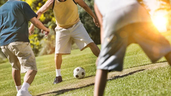 レンズフレアでロックダウン中に公園でサッカーをしている男性のグループ — ストック写真