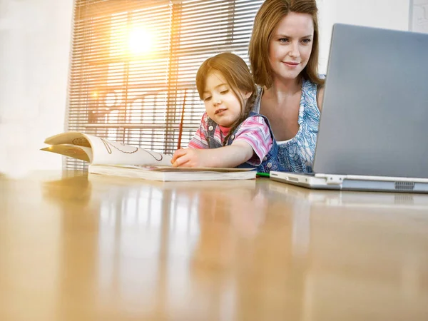 Junge Frau Arbeitet Mit Laptop Und Tochter Malt Buch — Stockfoto