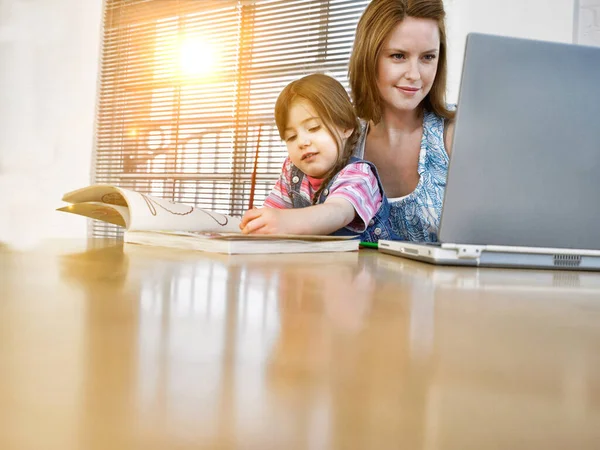Young Woman Working Laptop Her Daughter Colouring Book Stock Image