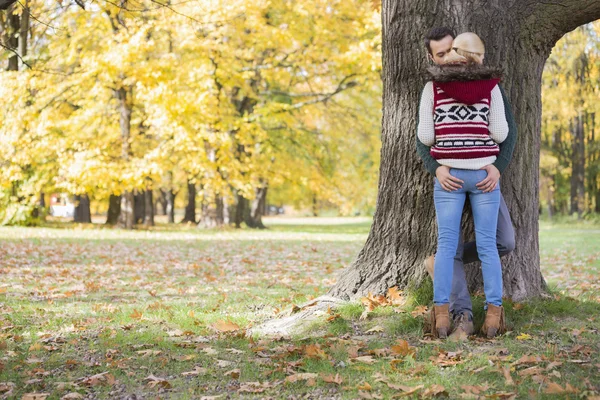 Couple standing against tree trunk — Stock Photo, Image