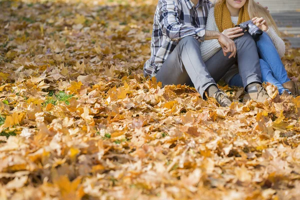 Pareja sentada sobre hojas de otoño — Foto de Stock