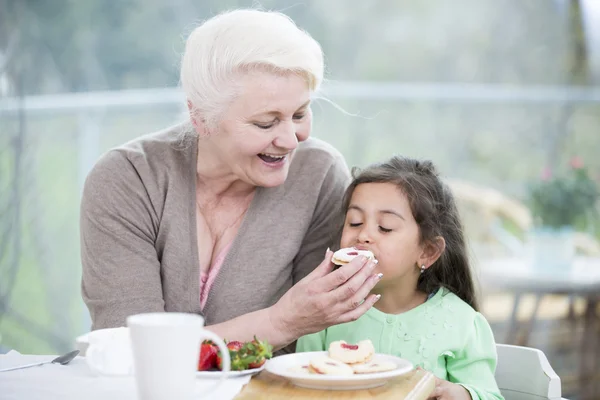 Woman feeding cookie to granddaughter — Stock Photo, Image