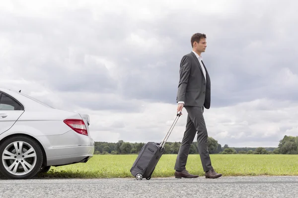 Businessman with suitcase leaving broken down car — Stock Photo, Image