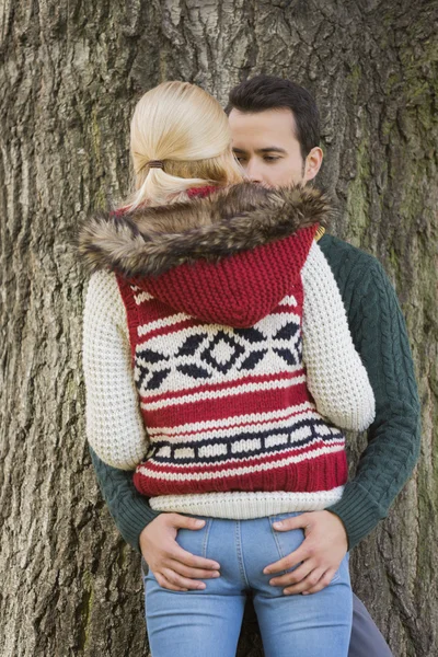 Pareja de pie contra tronco de árbol — Foto de Stock