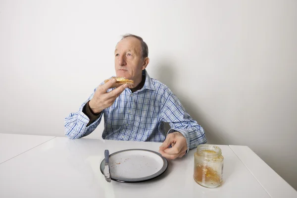 Hombre comiendo pan untado con mermelada de jalea dulce — Foto de Stock