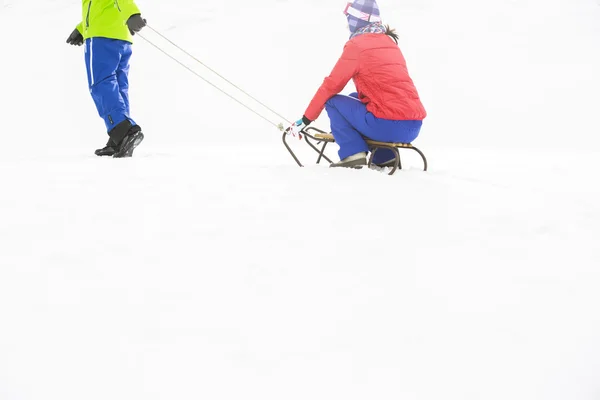 男人拉扯女人在雪橇上 — 图库照片