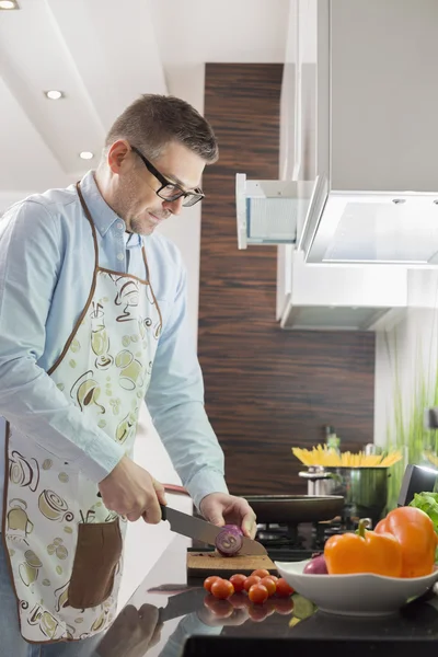 Homme coupant des légumes au comptoir de cuisine — Photo